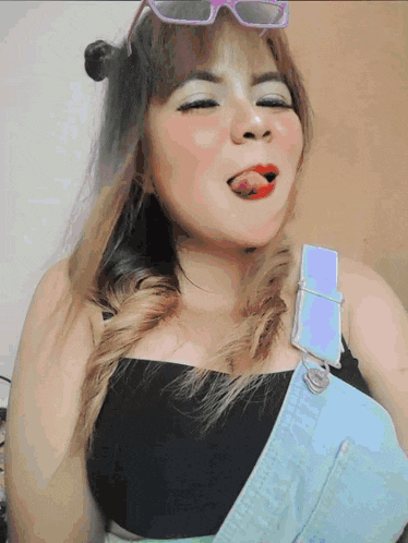 a woman wearing overalls is sticking her tongue out