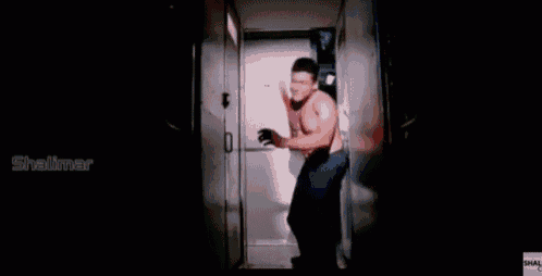 a shirtless man wearing boxing gloves is standing in a hallway