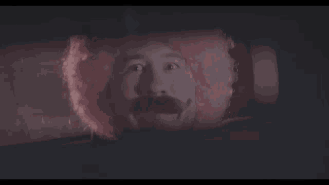 a man wearing a pink wig and a mustache is looking out of a car window .