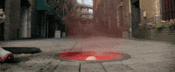a manhole cover is filled with red liquid and a baseball is coming out of it