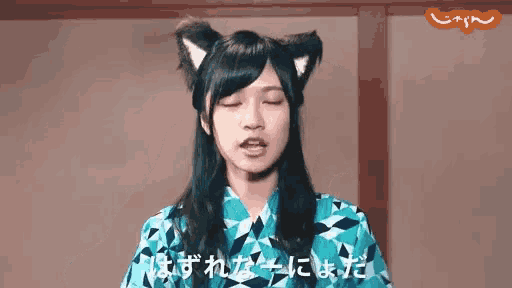 a woman wearing cat ears and a blue kimono is making a face .