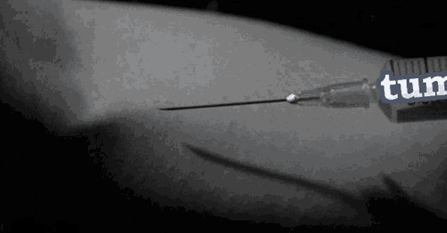 a black and white photo of a syringe with the word tum on the side
