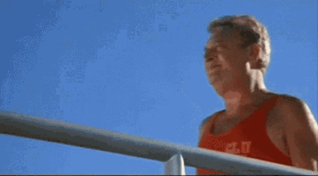 a man wearing a red tank top that says a.c.u.t. on it