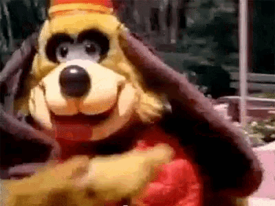 a close up of a stuffed animal in a red and yellow outfit with a hat on .