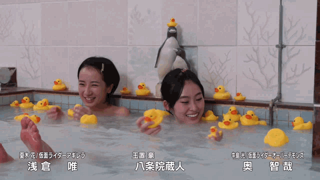 two women are playing with rubber ducks in a bathtub with chinese writing on the bottom