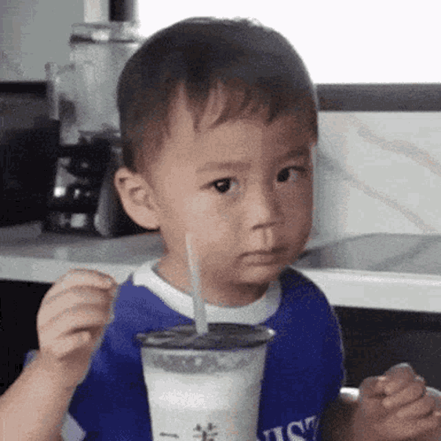 a young boy is drinking a milkshake with a spoon .