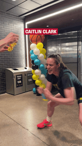 a woman squatting in front of a trash can that says recycling only
