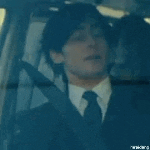 a man in a suit and tie is sitting in a car with another man .