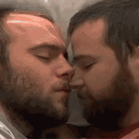 two men are kissing each other on the forehead in a bathroom .