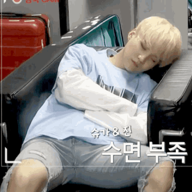 a man in a blue shirt is sleeping in a chair with asian writing behind him