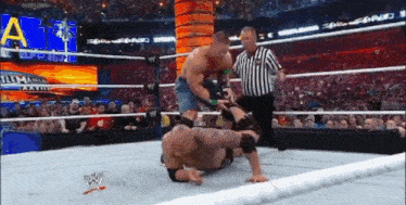 two men are wrestling in a wrestling ring with a referee watching .