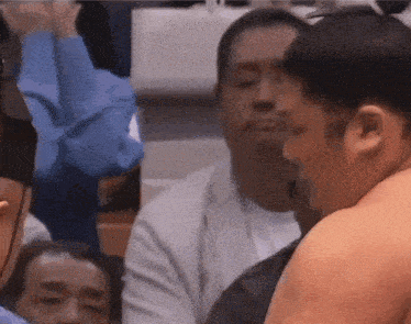 a group of men are watching a sumo wrestler in a ring