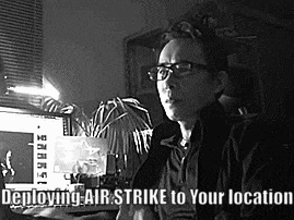a man wearing glasses is sitting in front of a computer with the words deploying air strike to your location below him