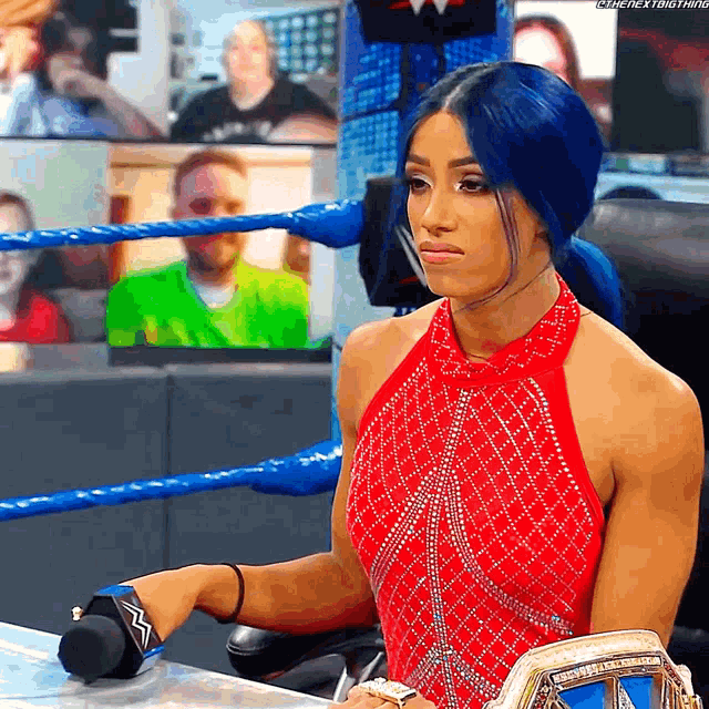 a woman in a red dress is holding a wrestling belt