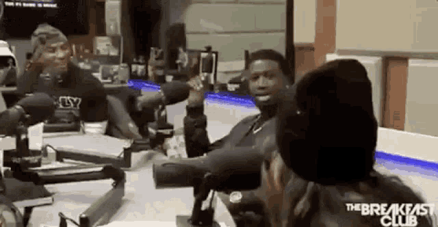 a group of people are sitting at a table in front of microphones in a studio .