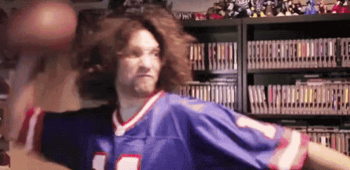 a man in a buffalo bills jersey is holding a basketball in his hands .