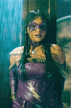 a woman in a purple superhero costume is tied to a pole in the rain