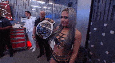 a woman in a wrestling outfit holds a wrestling championship belt