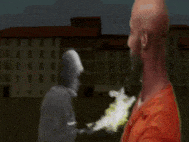a man in an orange shirt is standing in front of a statue of a man in a white hat