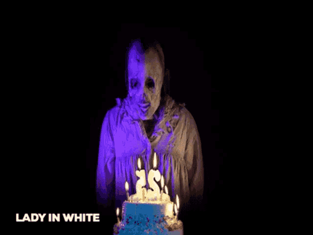 a lady in white is holding a birthday cake with candles on it