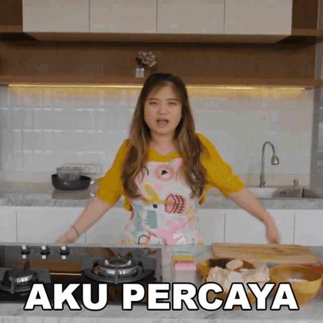 a woman in an apron is standing in a kitchen with the words aku percaya above her