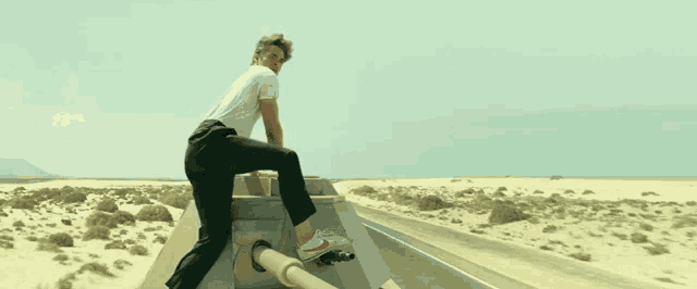 a man in a white shirt and black pants is standing on a pipe on the side of the road