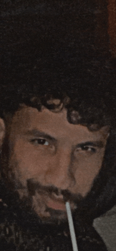 a man with a beard is smoking a cigarette with a straw in his mouth