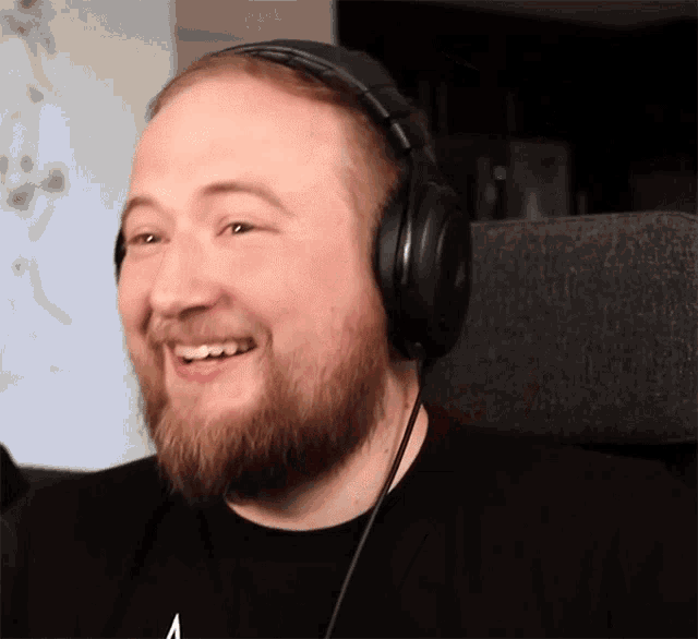 a bearded man wearing headphones is smiling