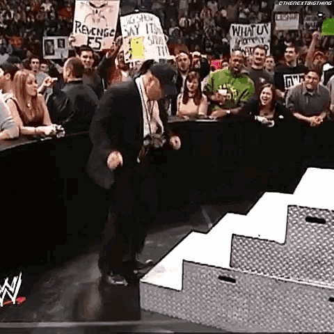 a man is dancing in front of a crowd while holding a sign that says revenge