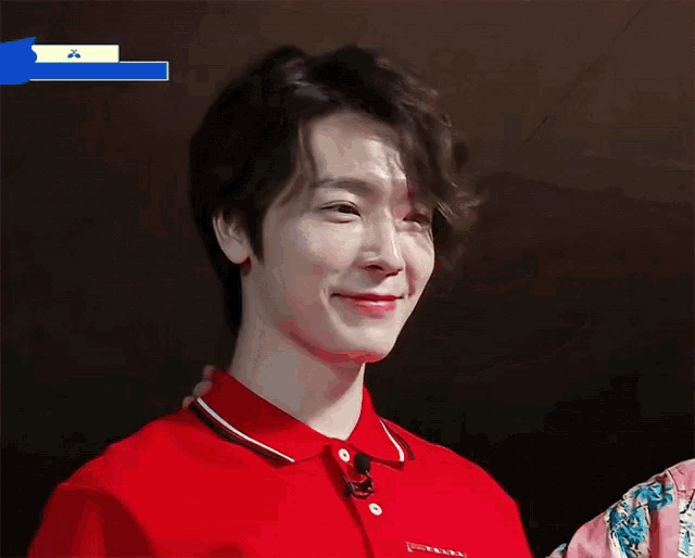 a young man wearing a red shirt is smiling and looking at the camera .