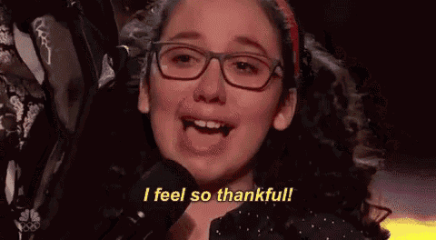 a young girl wearing glasses is crying while singing into a microphone and saying `` i feel so thankful '' .