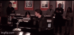 a man is playing a piano in front of a group of people in a room .