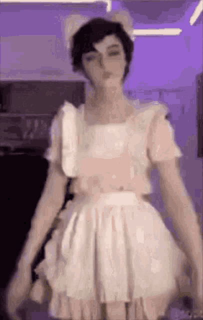 a man in a maid costume is standing in a room with a purple background .
