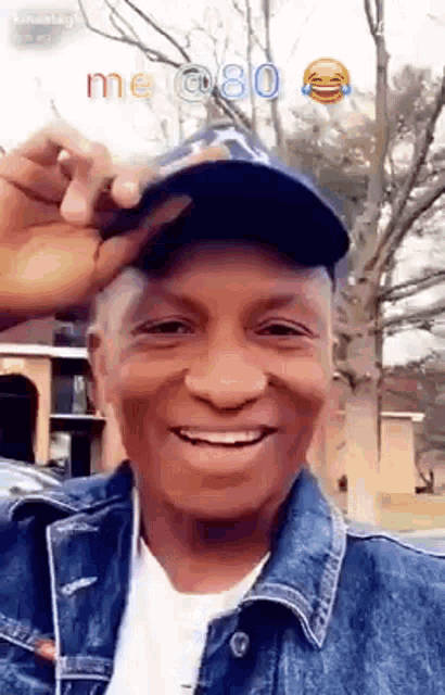 a man wearing a denim jacket and hat is smiling .