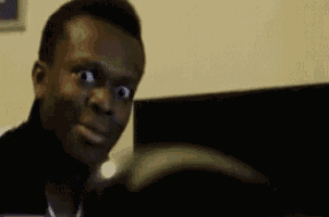 a man is making a funny face while looking at a computer monitor .