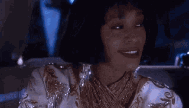 a woman in a white and gold dress is smiling in a car .