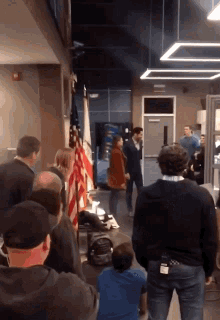 a group of people are gathered in a room with an american flag