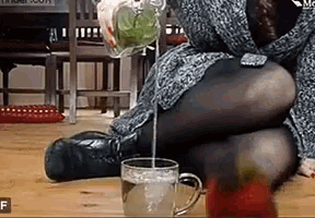 a woman is sitting on the floor pouring water into a glass .
