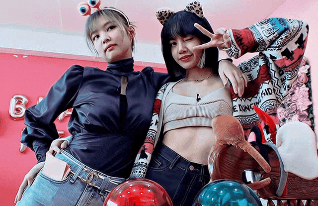 a woman wearing a headband with googly eyes stands next to another woman wearing jeans