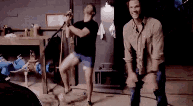 two men are standing next to each other in a room dancing .