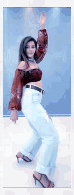 a woman in a crop top and blue jeans is dancing