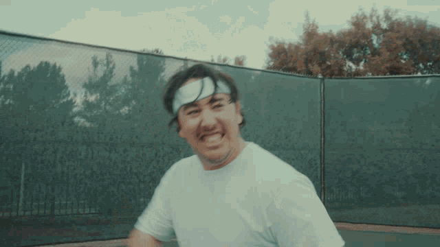 a man wearing a headband and a white shirt is playing tennis