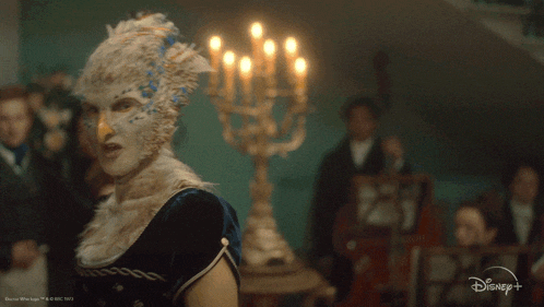 a woman in a bird costume is standing in front of a candle holder that says " you "