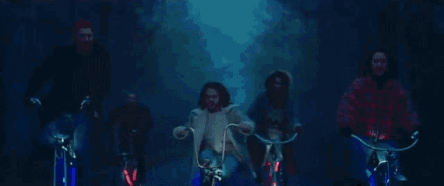 a group of people are riding bicycles down a road at night .