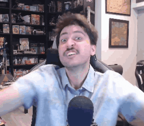 a man with a mustache is sitting in front of a microphone and making a funny face