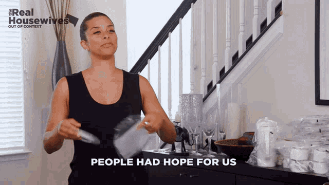 a woman in a black tank top stands in front of a staircase with the words " people had hope for us "