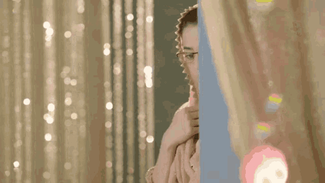 a woman wearing glasses and a veil looks out a window