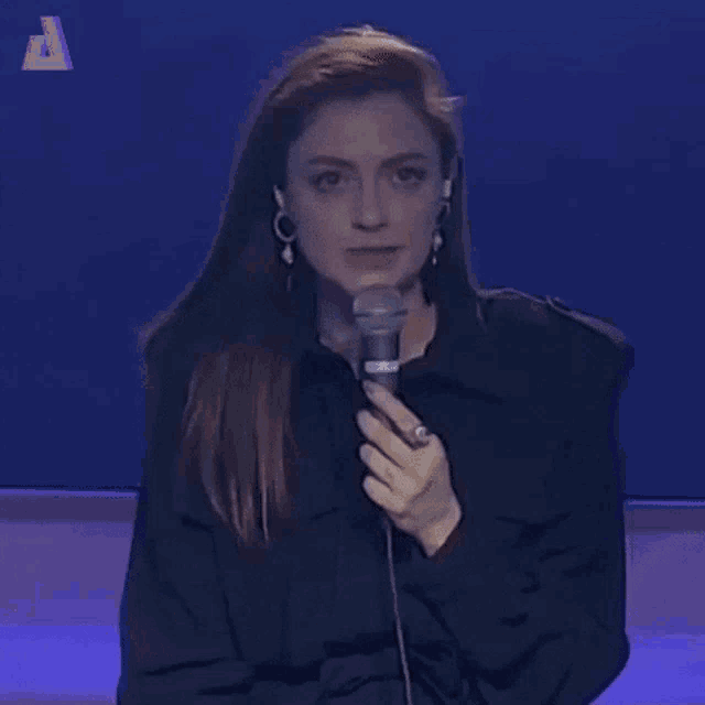 a woman is holding a microphone in her hand and making a face .