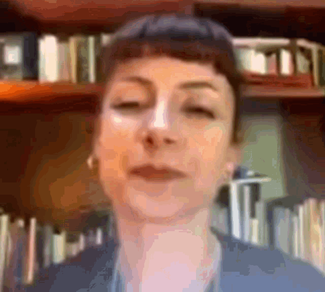 a blurry picture of a woman 's face in front of a bookshelf .