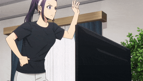 a woman in a black shirt is standing in front of a tv